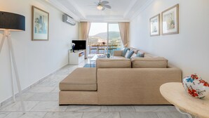 Un moderno salón con un sofá color beige, una mesa de comedor y vistas al exterior.