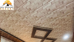 Un lit double avec une couvre-lit à motifs floraux et plusieurs oreillers, une tête de lit en bois et un plafond orné d’un motif imitant des briques.