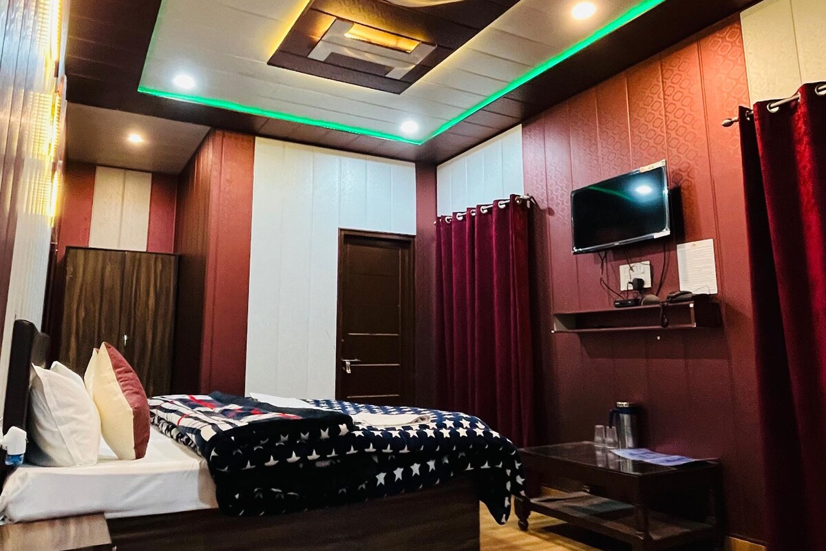 A modern bedroom with a large bed, a flat-screen TV, and a wooden floor.