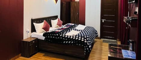 Quarto com cama, mesas de cabeceira, cômoda e escrivaninha com cadeira.