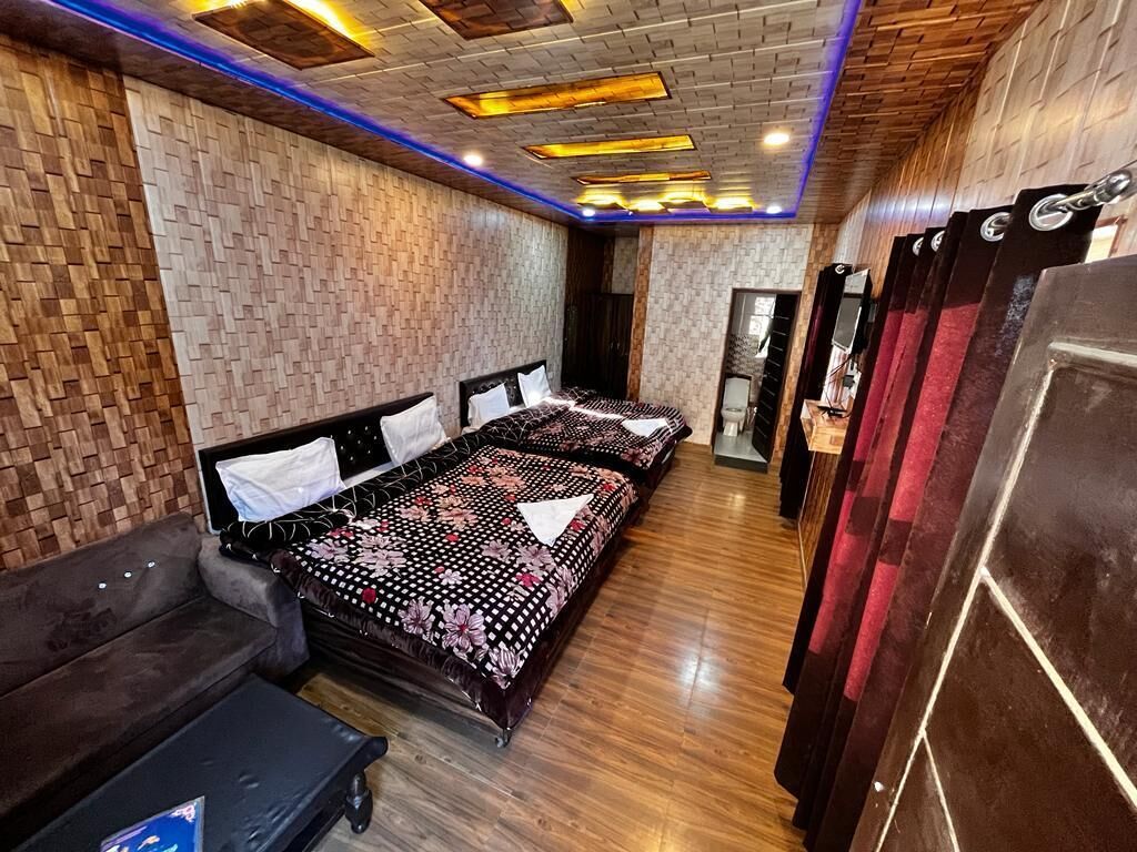 Una habitación de hotel con techo de madera, una cama con colcha estampada, un sofá y una pequeña mesa.