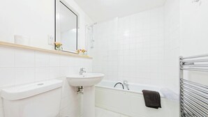 Een badkamer met toilet, wastafel en bad.