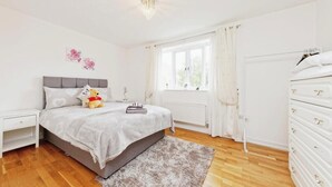 Een slaapkamer met een bed, nachtkastje, kast en raam met gordijnen.