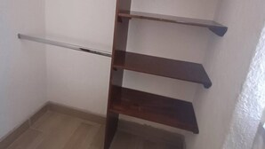 Eine Ecke mit einer Holzeinheit an einer weißen Wand, mit mehreren Regalen und einer waagerechten Stange.
