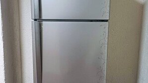 Ein Edelstahl-Kühlschrank mit Zweitürdesign, steht in einer Raumecke mit Holzboden und hellen Wänden.