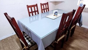 Ein Esstisch mit Glasplatte, umgeben von Holzstühlen mit gepolsterten Sitzflächen.