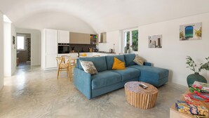 Un salon moderne avec un canapé bleu, une table basse en bois et une cuisine en arrière-plan.