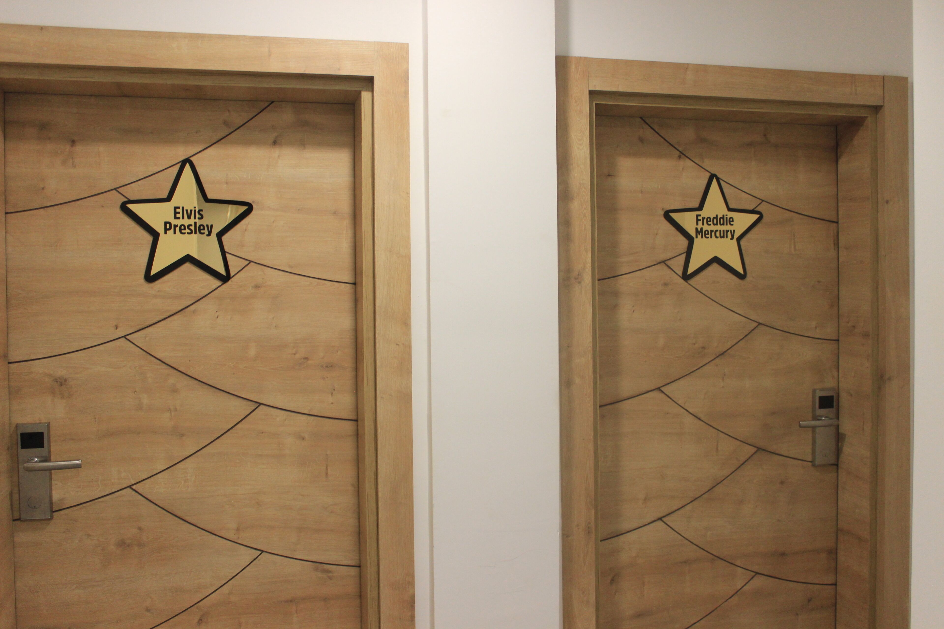 Two wooden doors with star-shaped signs, one labeled "Elvis Presley" and the other "Freddie Mercury".