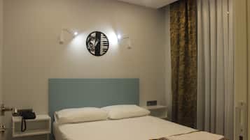 Et hotelværelse med en seng, et natbord med telefon og et vægur.