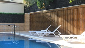 A swimming pool with white lounge chairs and a wooden fence.