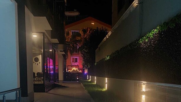 A nighttime view of a modern building with a pool area, illuminated by ambient lighting.