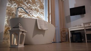 A modern bathroom with a freestanding bathtub, a small lantern, and a mounted TV. - Palazzo Carella (Palermo)