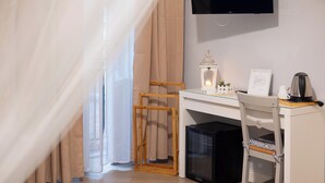 A bedroom with a desk, a TV mounted on the wall, a bed with a curtain, and a small table with a lantern and a kettle. - Palazzo Carella (Palermo)