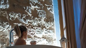 A woman sitting in a large, freestanding bathtub with a towel on the floor in front of her. - Palazzo Carella (Palermo)