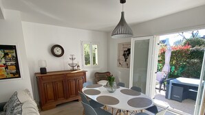 A modern dining area with a round table, blue chairs, and a hanging pendant light. - TYKLAN house in Bénodet (Bénodet)