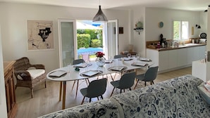 A dining area with a table set for four, a wicker chair, a sofa, and a view of the outdoors. - TYKLAN house in Bénodet (Bénodet)