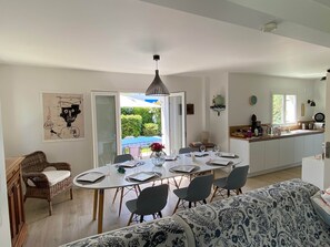 A dining area with a table set for four, a wicker chair, a sofa, and a view of the outdoors. - TYKLAN house in Bénodet (Bénodet)