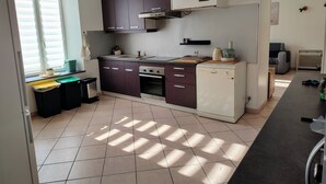 A kitchen with a stove, oven, and microwave, a window with blinds, and a trash bin. - Comfortable cottage with fireplace and parking, near Verdun (Dompcevrin)