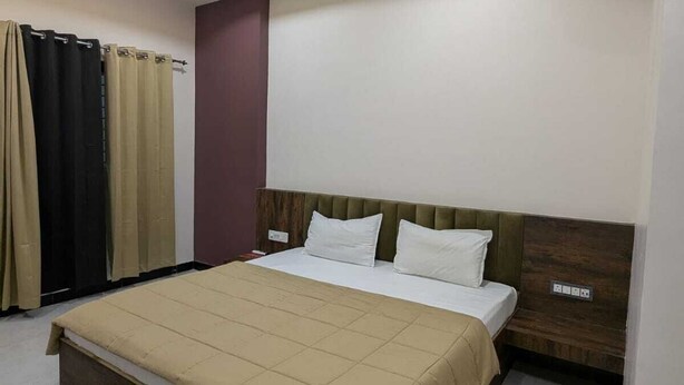 A modern hotel room with a large bed, a ceiling fan, recessed lighting, and an air conditioning unit. - Hotel Dhruvnanda Palace Khategaon (Khategaon)