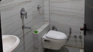 A bathroom with a marble wall, a toilet, a sink, and a shower. - Hotel Dhruvnanda Palace Khategaon (Khategaon)