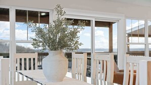 A dining area with a white table, white chairs, a white vase with greenery, and large windows with a view. - Gorgeous Lake View! Indoor Pool! 5 Min to Branson Strip! (Branson)