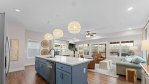 A modern kitchen with a central island, a dining area with a table and chairs, and a living room with a sofa and a lamp. - Gorgeous Lake View! Indoor Pool! 5 Min to Branson Strip! (Branson)