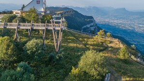 Un chalet de montagne doté d’une terrasse en bois offrant une vue sur une vallée.