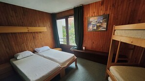 A room with two bunk beds, a window with curtains, and a wall-mounted picture.
