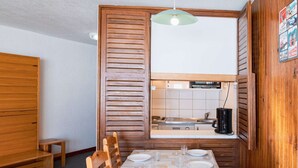 A compact kitchen with wooden cabinets, a built-in oven, and a hanging light fixture.