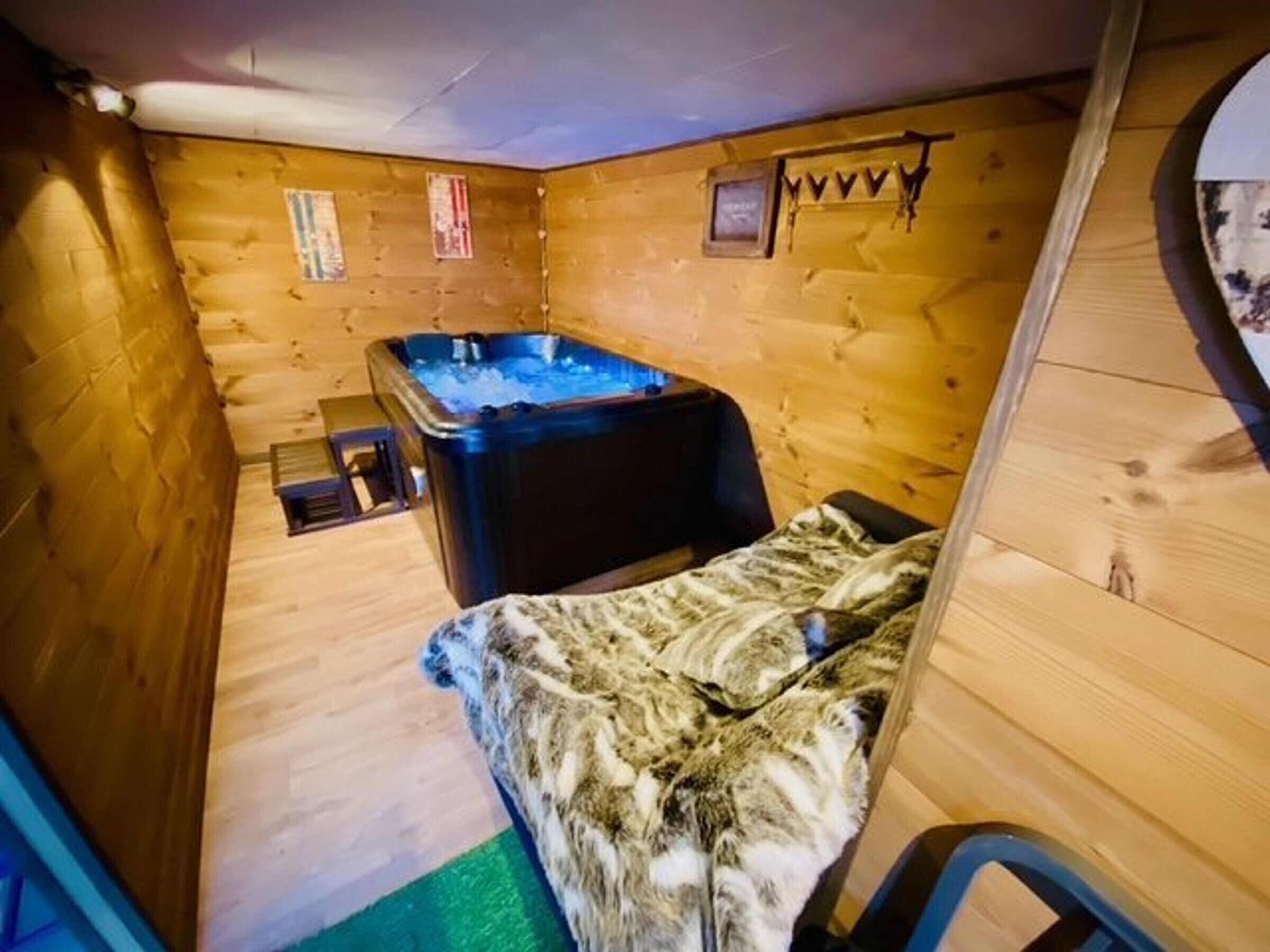 Een knus, klein kamertje met houten inrichting, een jacuzzi en een bed met een gestreept deken.