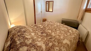 A bedroom with a bed, a dresser, a mirror, and a door. - Apartment Vars, 2 bedrooms, 4 persons (Vars)