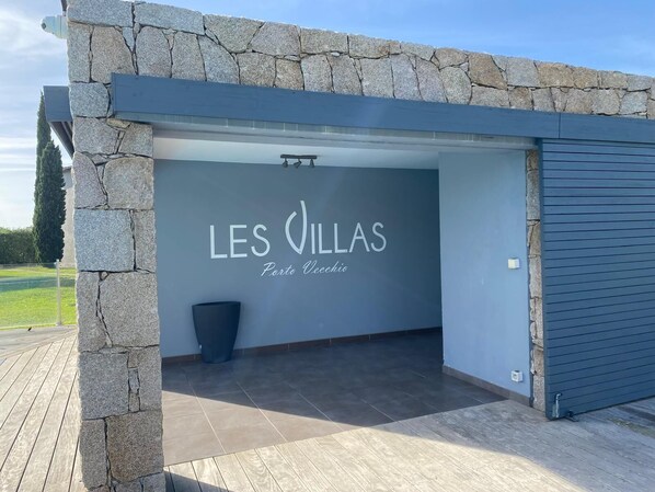 A modern building with a stone facade and a sign that reads "LES VILLAS Porto Vecchio."