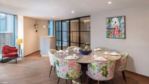 A dining area with a round table, floral chairs, and a painting on the wall.