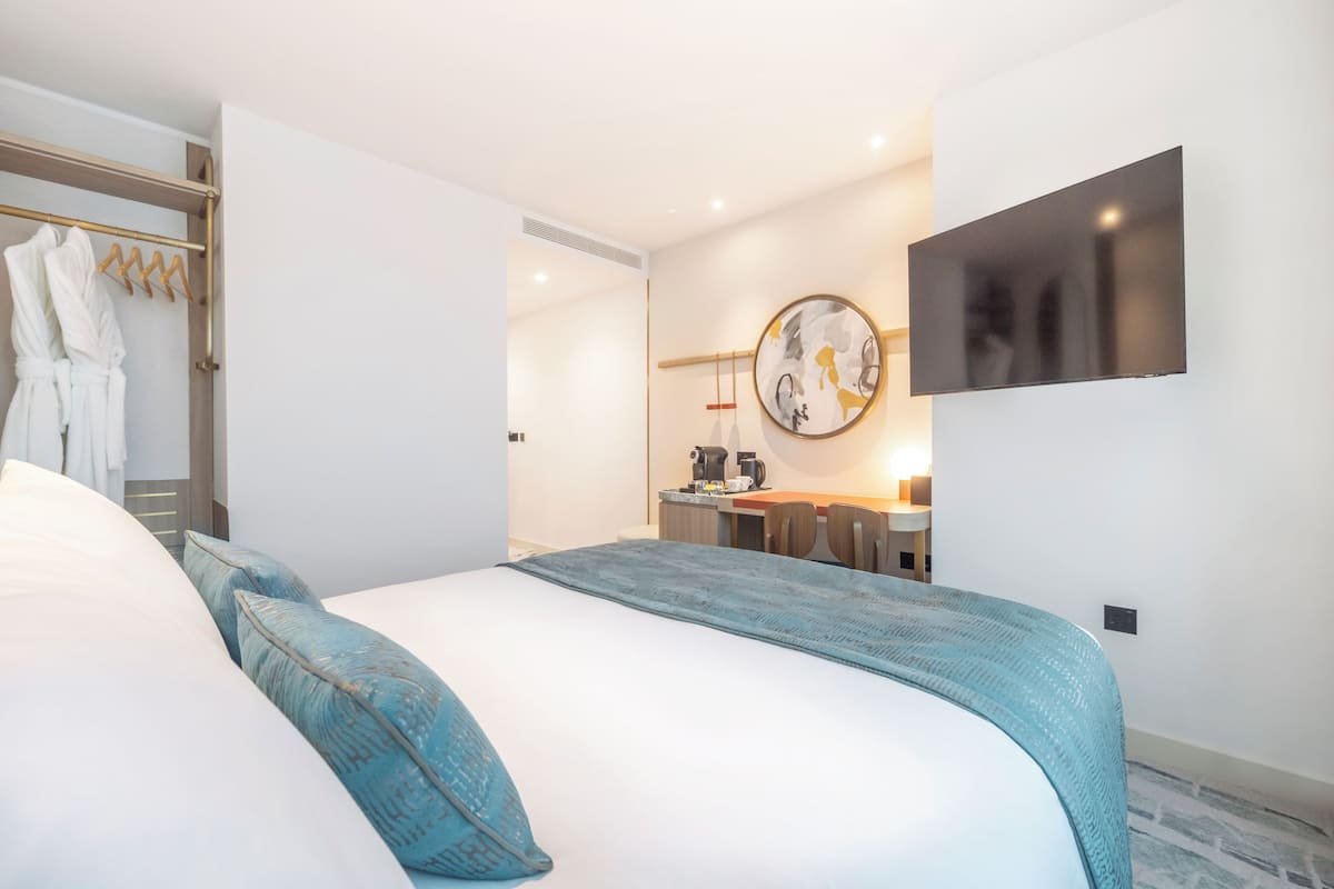 Une chambre d’hôtel moderne, dotée d’un grand lit, d’un bureau et d’une télévision.