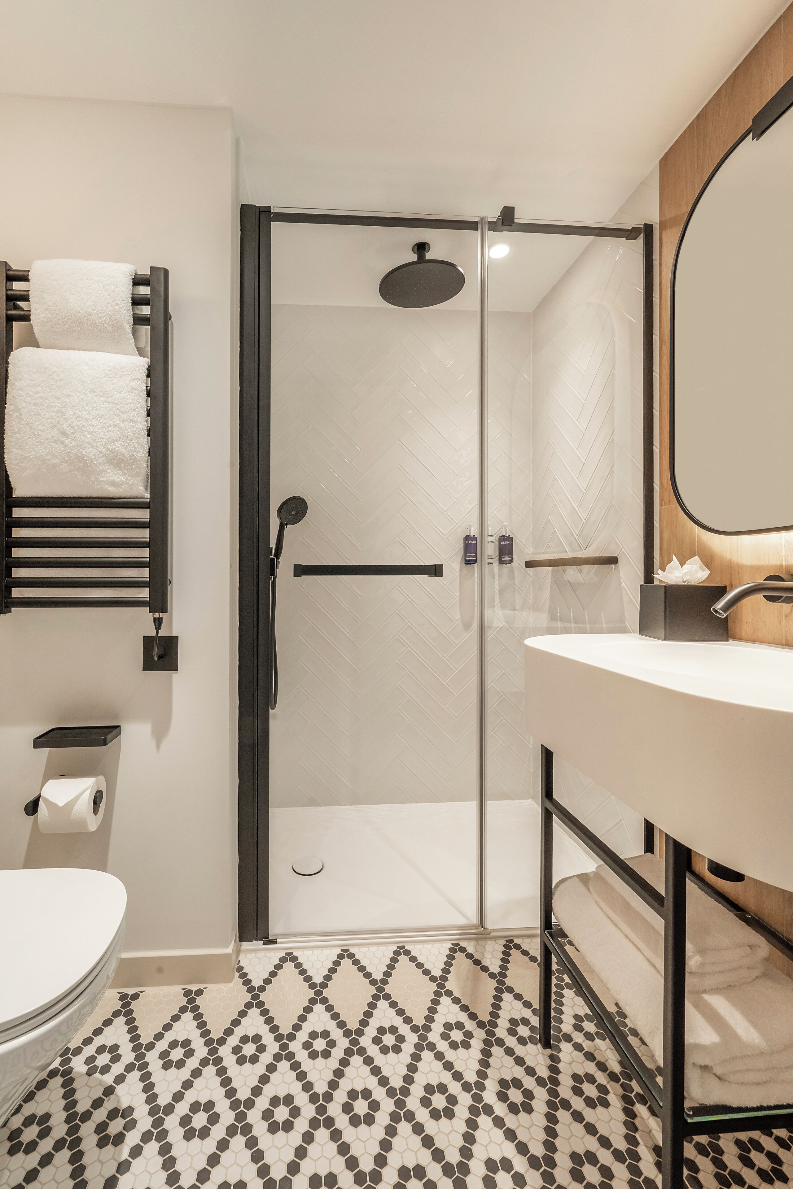 A modern bathroom with a glass-enclosed shower, a white sink, and a patterned floor.