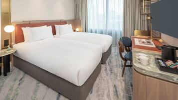 A hotel room with two beds, a desk with a computer, a chair, and a coffee maker.