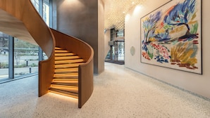 A modern interior with a spiral staircase, a large abstract painting, and a speckled floor.
