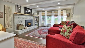 A living room with a fireplace, red sofa, and a large window with curtains.