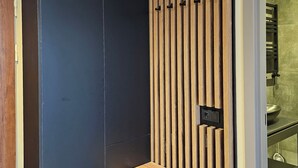 A modern bathroom with a dark wall, a wooden slatted panel, and a small wooden bench. - King David equipped luxury one bedroom10 (Tbilisi)