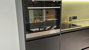 A modern kitchen with a built-in oven, a microwave, and a stainless steel countertop. - King David equipped luxury one bedroom10 (Tbilisi)