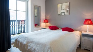 A bedroom with a large bed, two bedside tables, a window with a view, and a painting on the wall. - Alpine ski Apartment Getaway (Bad Gastein)