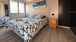 Un dormitorio con cama, mesita de noche y un cuadro en la pared.