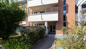 Un edificio residencial de varios pisos con una entrada central, un espacio exterior cubierto y fachada de ladrillo.