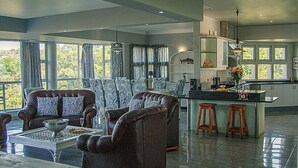 Een ruime woonkamer met een groot raam, een eethoek en een keuken met een centraal kookeiland.