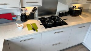 Eine moderne Küche mit weißen Schränken, einer Edelstahl-Dunstabzugshaube und einem Gasherd.