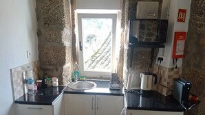 A compact kitchen with a window, a sink, and a coffee machine.