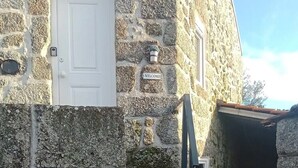 A stone building with a white door and a welcome sign.