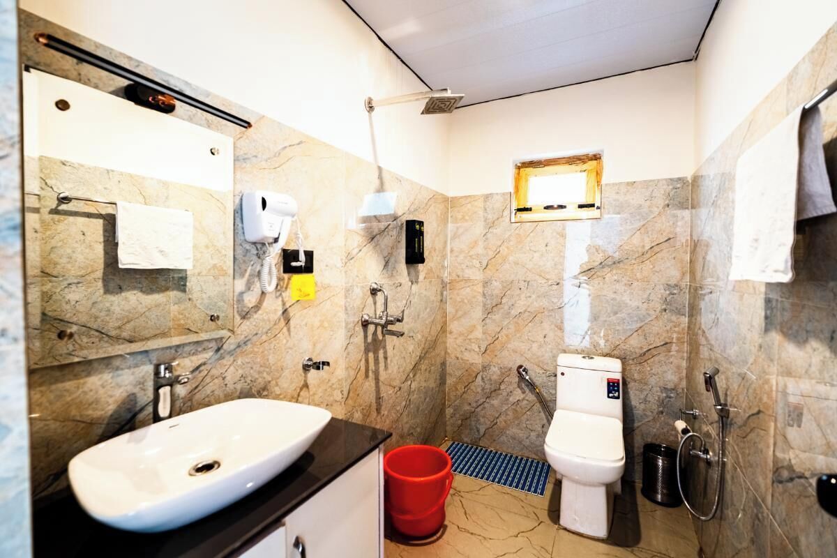 A modern bathroom with a marble sink, a toilet, a shower, and a hand dryer.