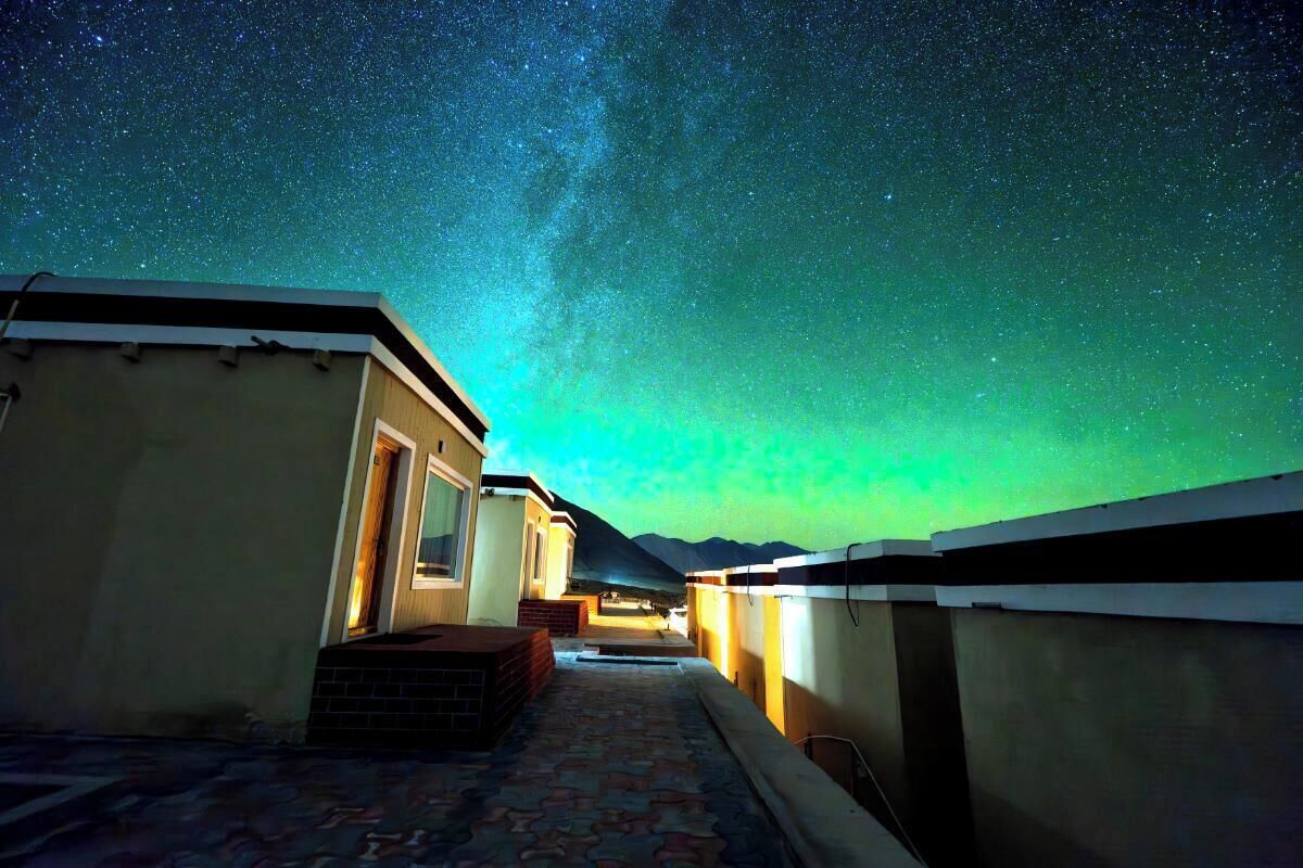 A corridor with a view of the night sky, leading to a building with a door and windows.