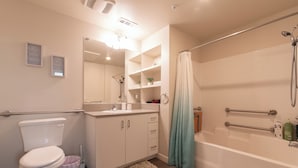 A modern bathroom with a toilet, sink, and bathtub. There are shelves above the sink and a shower curtain. - Santa Ana Delightful 4 Bedroom House (Santa Ana)